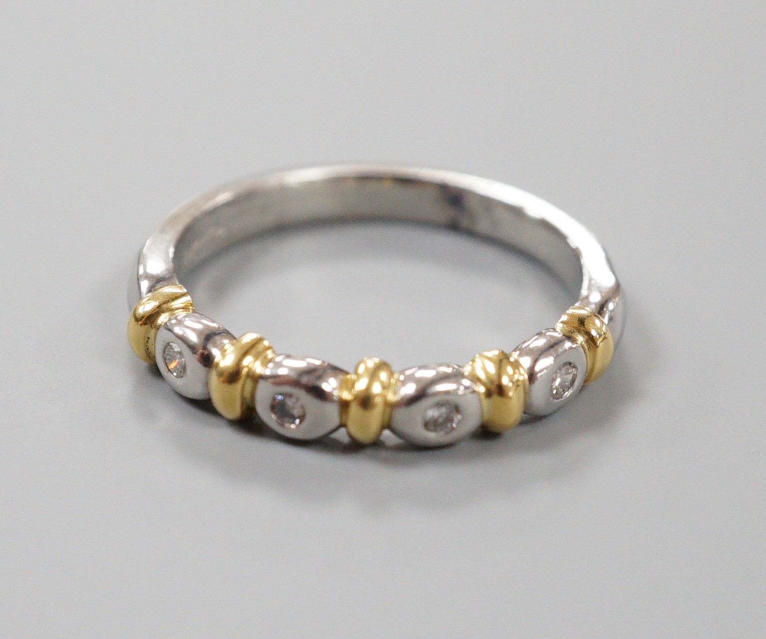 A modern platinum and yellow metal , four stone collet set diamond half hoop ring, size P, gross weight 6 grams